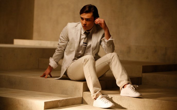 Ed Westwick in a white suit sitting on the stairs