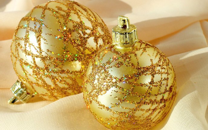 Two golden Christmas ornaments filled with glitter