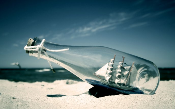 A ship in a bottle on the hot sand HD wallpaper