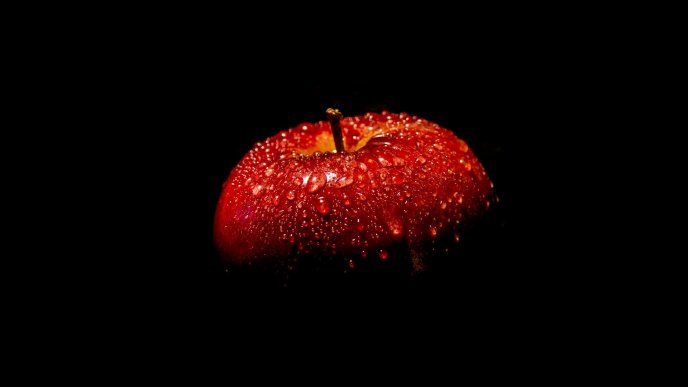 Red apple full with water drops in the dark