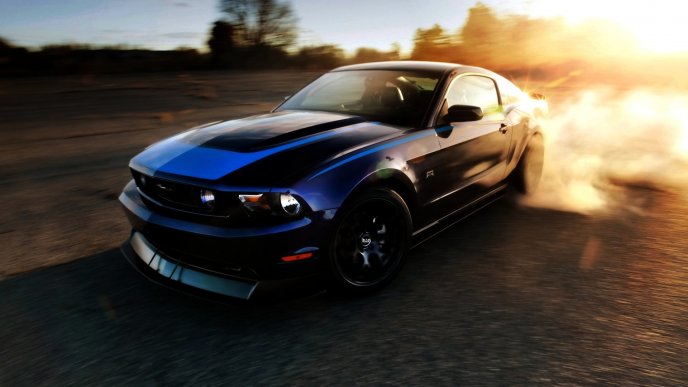 Blue Ford Mustang drifting at sunset