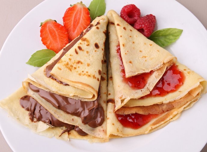 Delicious pancakes with chocolate and strawberry jam