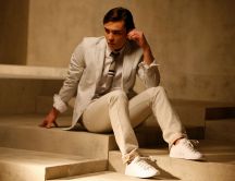Ed Westwick in a white suit sitting on the stairs