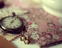 Old pocket clock, earrings and pink envelope on the table