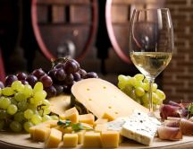Cheese specialties, prosciutto, grapes and a glass of wine