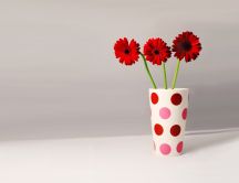 Three red gerbera in a vase with dots