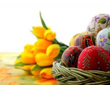Hand painted eggs in front and yellow tulips