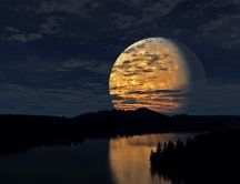 Big yellow moon reflected in river water