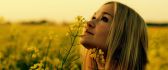 Beautiful blonde girl on a field full with yellow flowers