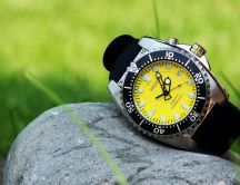 A watch in black and yellow on a stone