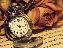 A golden clock beside the many roses on the book