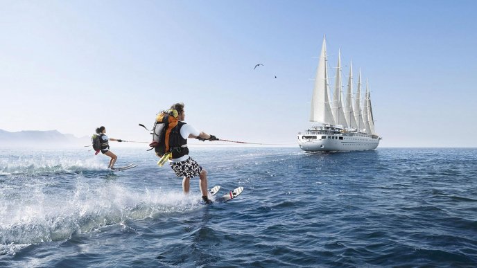 Sailboat on the ocean - two people skiing on water