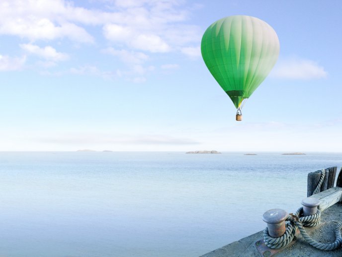 A green air balloon flies over the sea