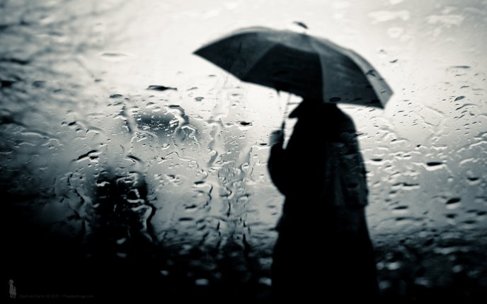 A man standing outside in the rain with an umbrella