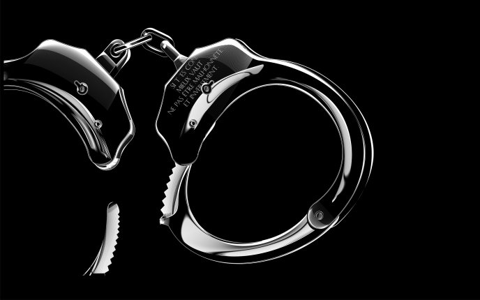 Silver handcuffs on a black wall