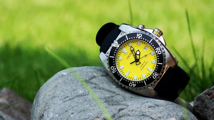 A watch in black and yellow on a stone