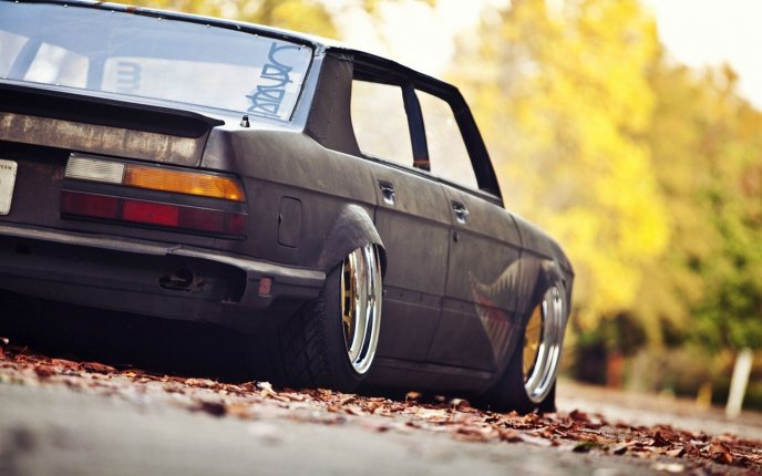 Old dark BMW car and Autumn leaves on the road