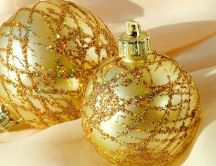 Two golden Christmas ornaments filled with glitter