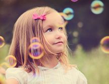 Sweet little blonde girl playing with soap bubbles