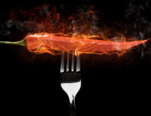 A fork with a hot red pepper in flames