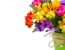 Colorful daffodils and freesias bouquet in a green vase
