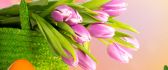 Bouquet of pink tulips and Easter eggs in the green grass