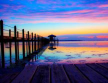Rainbow colors of sunset over the ocean water and pontoon