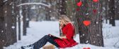 Beautiful blonde girl read a book in the snow - Love hearts